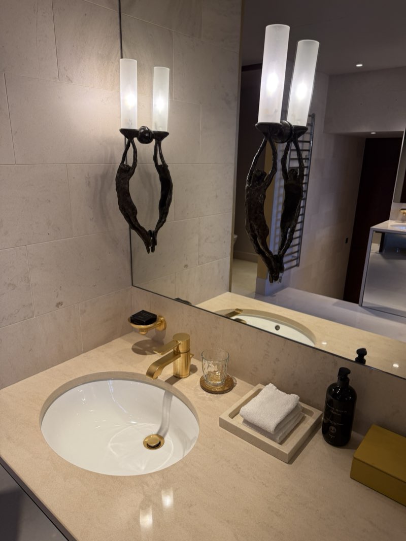 Bathroom vanity at the Park Hyatt Paris-Vendôme with a gold faucet and a bronze sculpture lamp