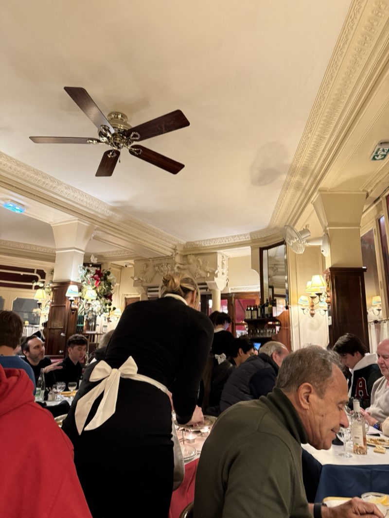 The dining room at Le Relais de Venise, with servers in black and white uniforms