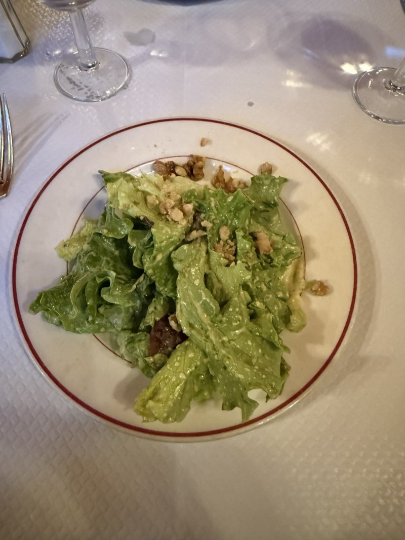 Green salad with walnuts on a red-rimmed plate at Le Relais de Venise