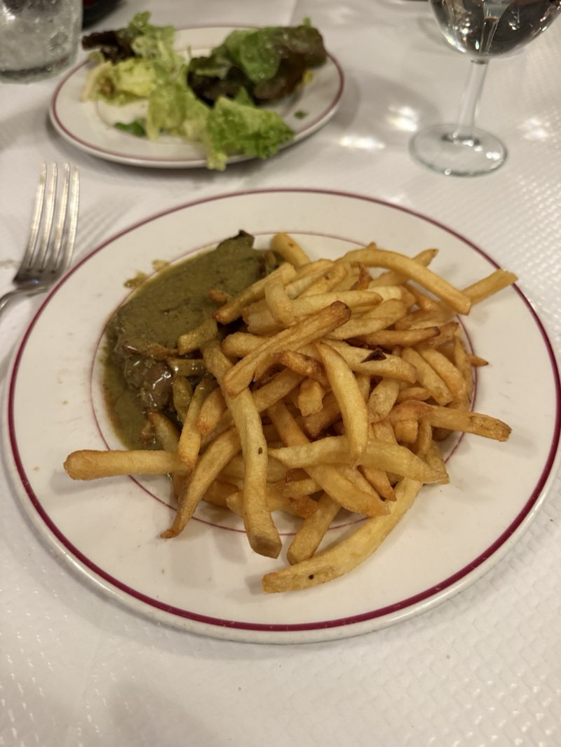 Steak-frites with the green sauce on a red-rimmed plate at Le Relais de Venise
